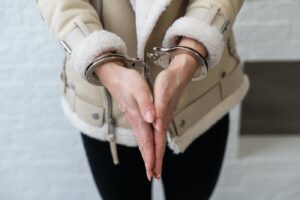 A woman in handcuffs being arrested while attorney prepares criminal case approaches for legal defense.