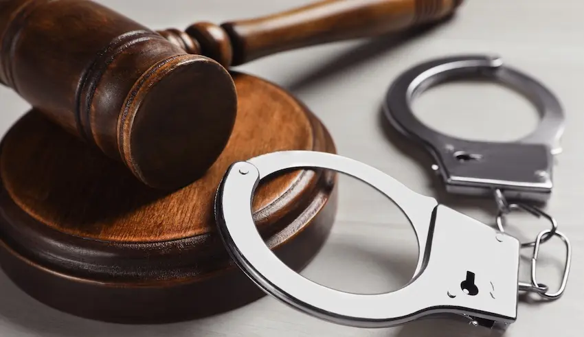 A wooden judge's gavel resting on its sound block beside a pair of open steel handcuffs on a gray surface symbolizing the criminal justice process and the role skilled legal representation from Byron Pugh Legal plays in determining criminal defense outcomes in Tennessee.